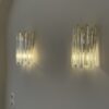 Pair of Murano triedri wall sconces lit on a warm wall