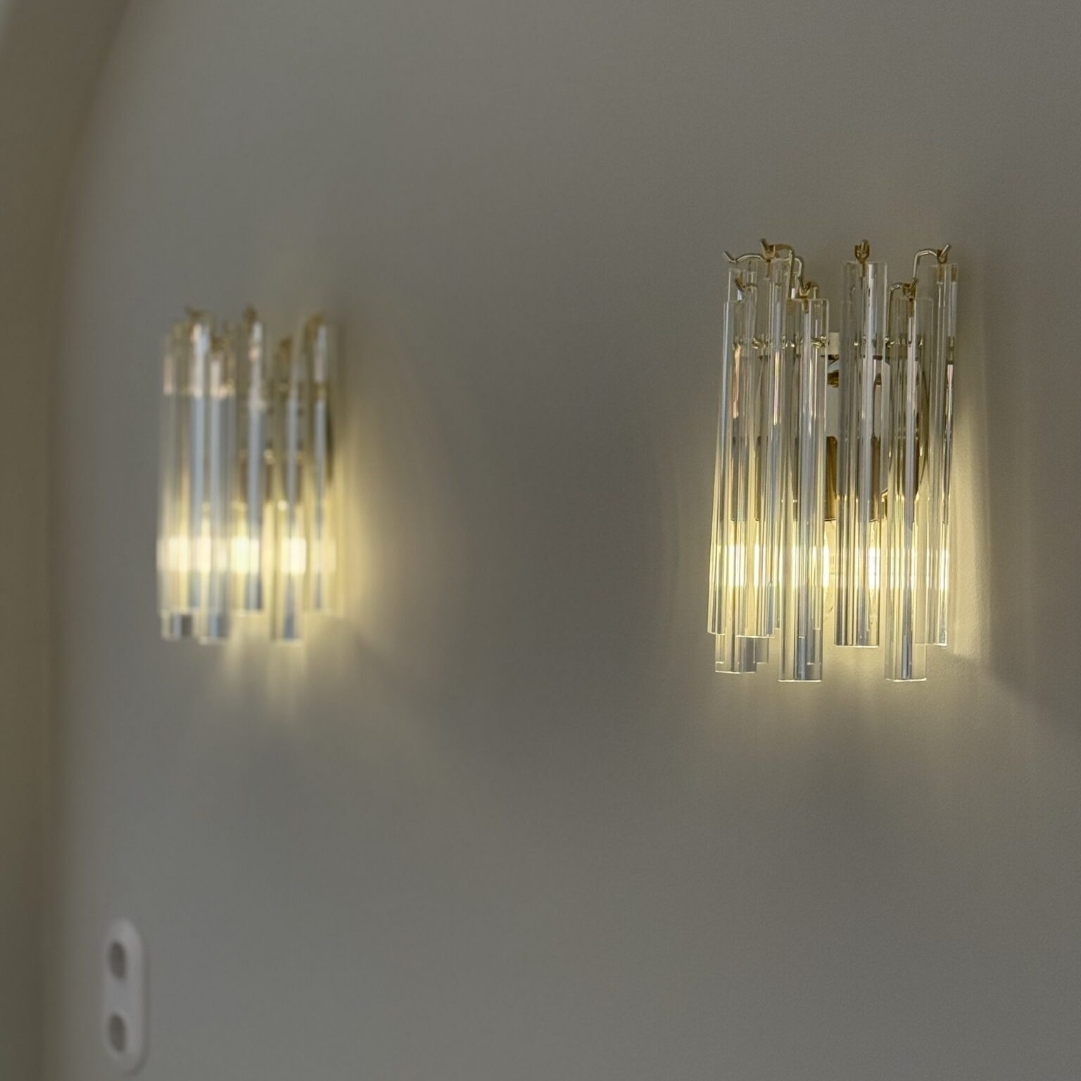 Pair of Murano triedri wall sconces lit on a warm wall